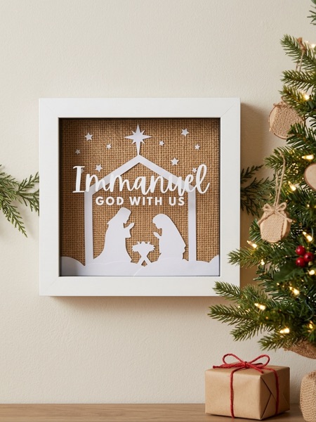 Christmas shadow box on hessian with a white nativity silhouette and the words Immanuel, God with us.